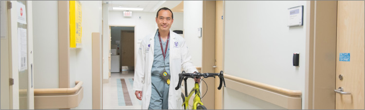 Dr. Fung walking down the hallway with his bicycle after his morning commute.
