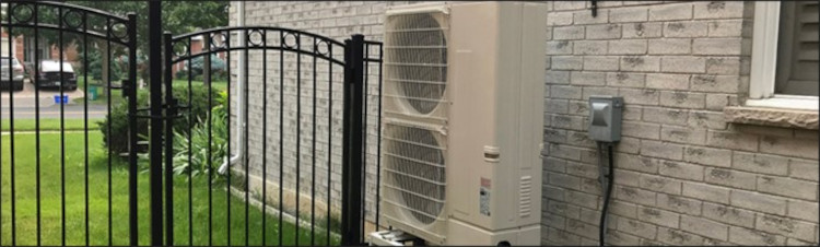 Residential cold climate heat pump installed next to a house.