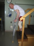 Image of a man demonstrating how to go down the stairs with two crutches