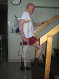 Image of a man demonstrating how to go up the stairs with one crutch and using a railing