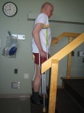 Image of a man demonstrating how to go up the stairs with one crutch and using a railing