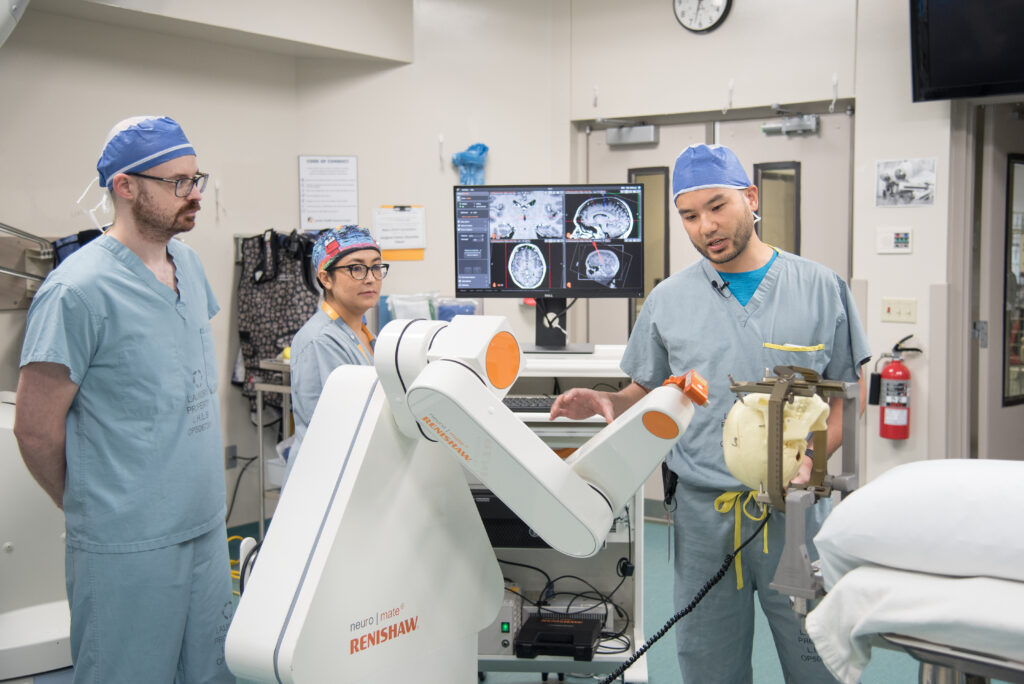 Neurosurgeon Dr. Jonathan Lau (right), Neurophysiologist Dr. Greydon Gilmore and Dr. Sonia Mejia, an epilepsy fellow from Mexico City, with robot used to assist in first deep brain stimulation surgery to treat epilepsy in Canada. 