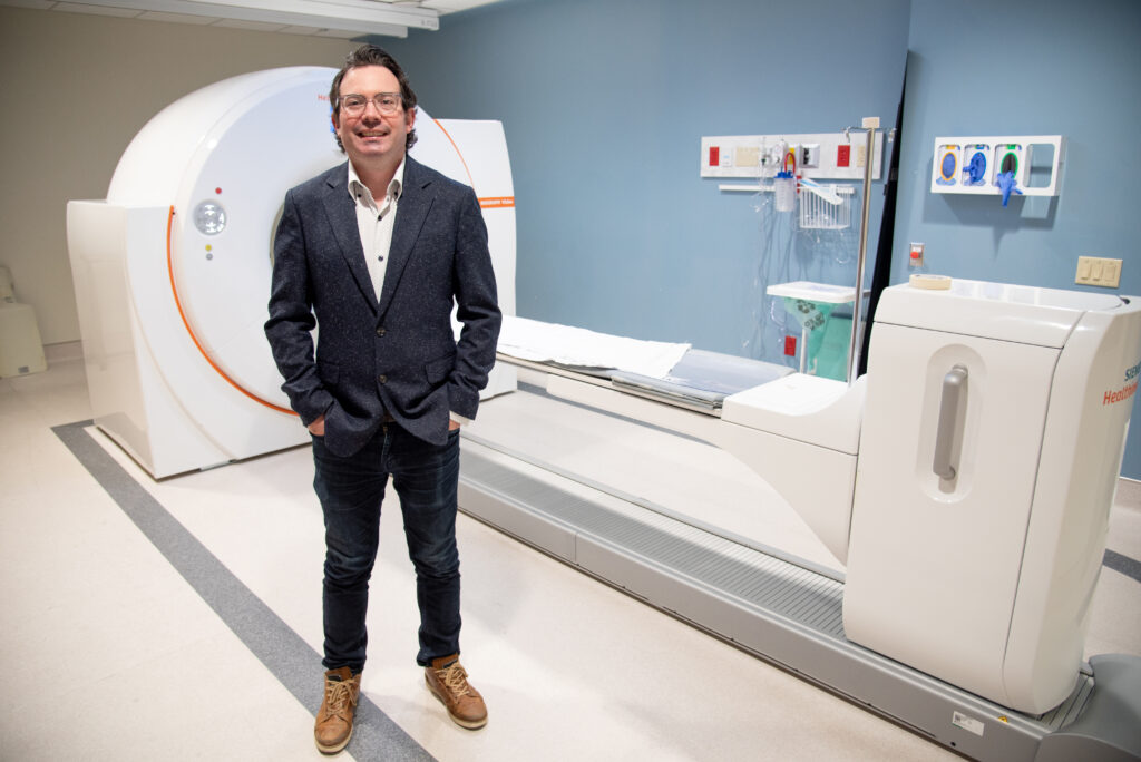 Dr. David Laidley, Associate Scientist at  LHSCRI and Nuclear Oncologist at LHSC, in front of a positron emission tomography (PET) machine where novel radiation treatments for cancer patients are being researched. 