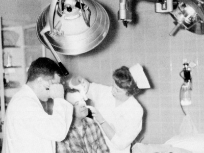 Nurse helping a patient in one of the operating rooms in the Emergency Departments (circa 1960).