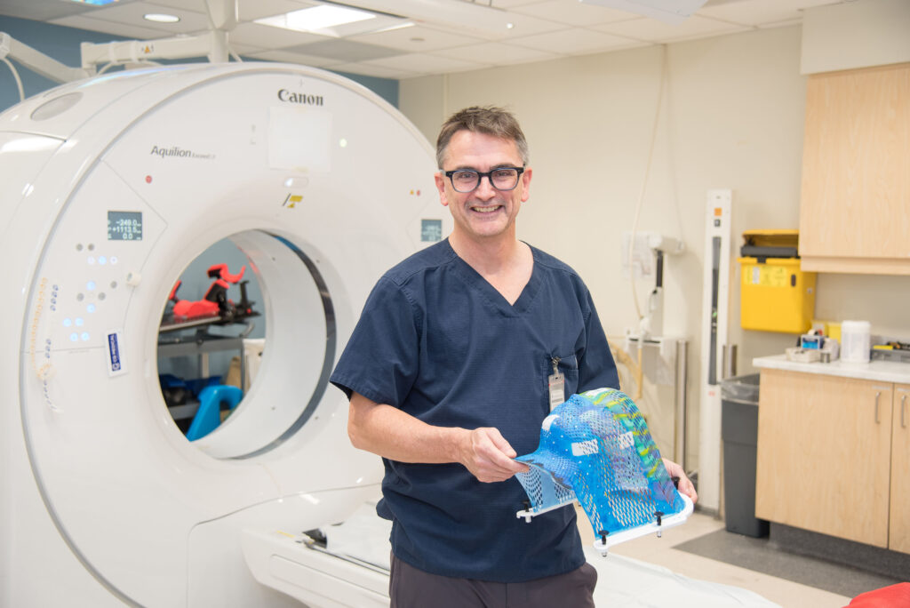 Dr. Bauman holding a thermoplastic mask that helps patients stay still during radiation treatment. 