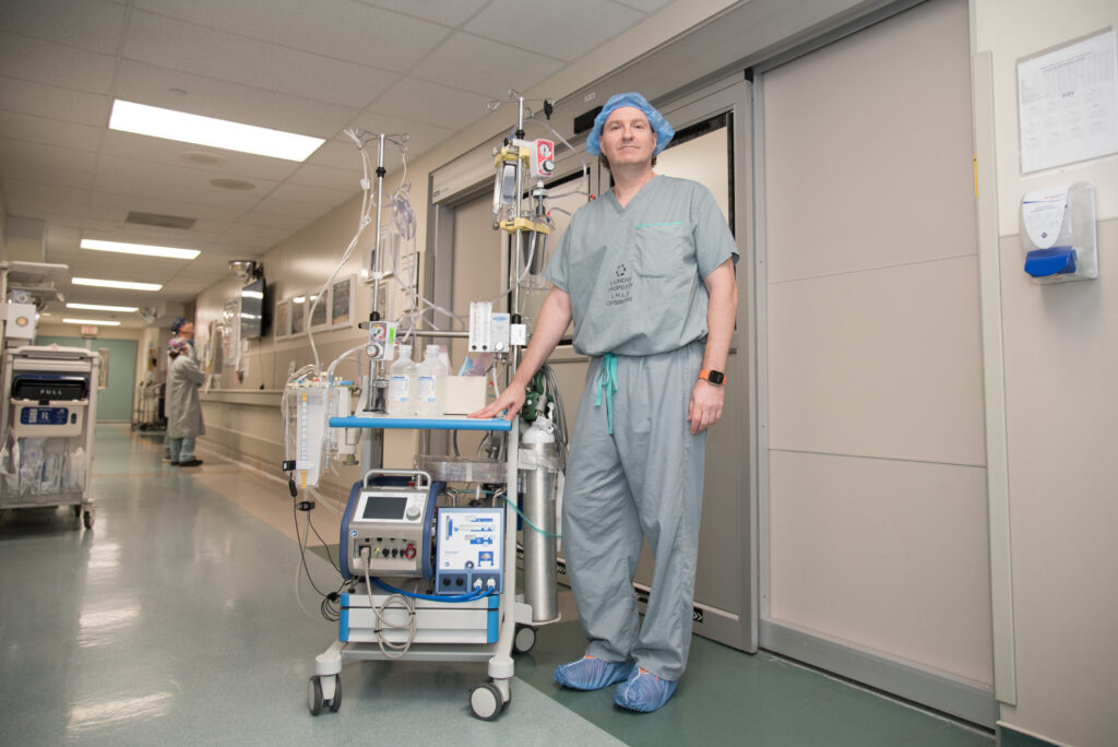 Dr. Skaro at LHSC’s University Hospital standing next to the pump that is used to recirculate blood to organs being prepared for donation. 