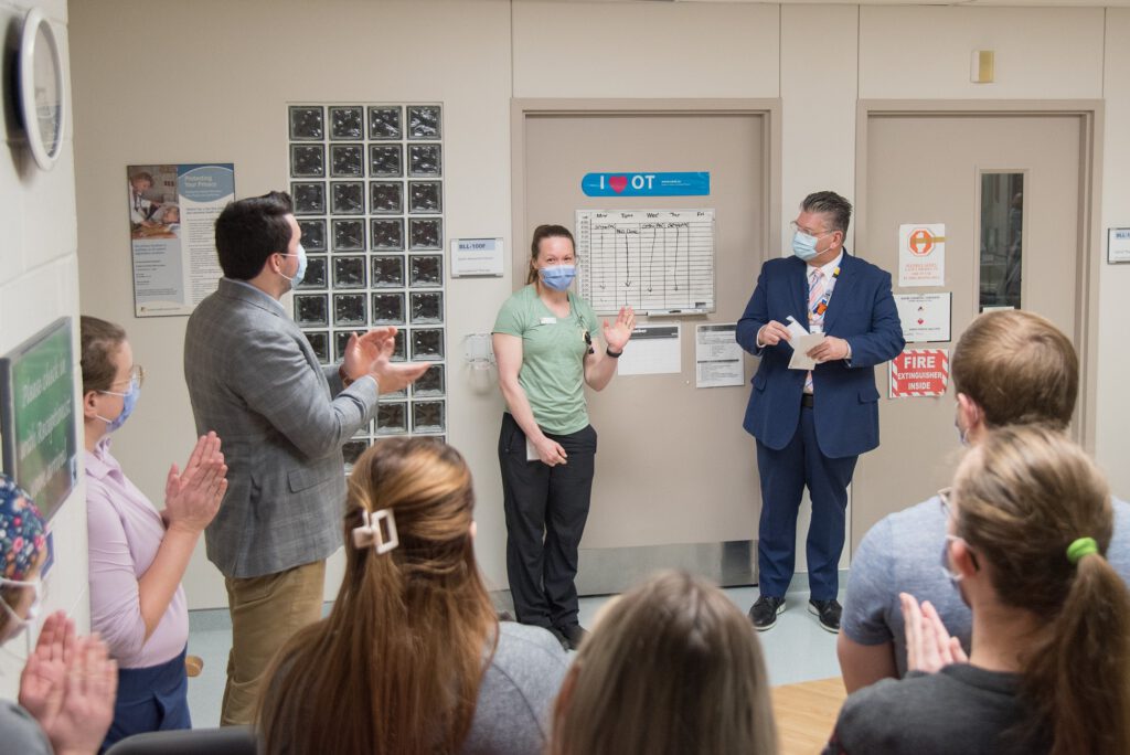 Cindy Fehr, OT/PT Assistant, and November prize winner, receives her letter and prize from David Musyj surrounded by her colleagues.