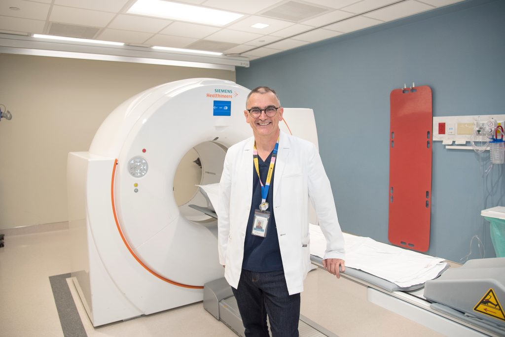 Dr. Glen Bauman, Scientist at LHSCRI and Radiation Oncologist at LHSC, stands in front of the positron emission tomography (PET) scanner.