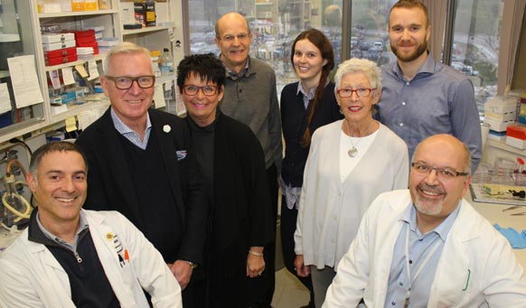 Three females and five males (two of which are doctors) posing for a photo in a hospital laboratory.