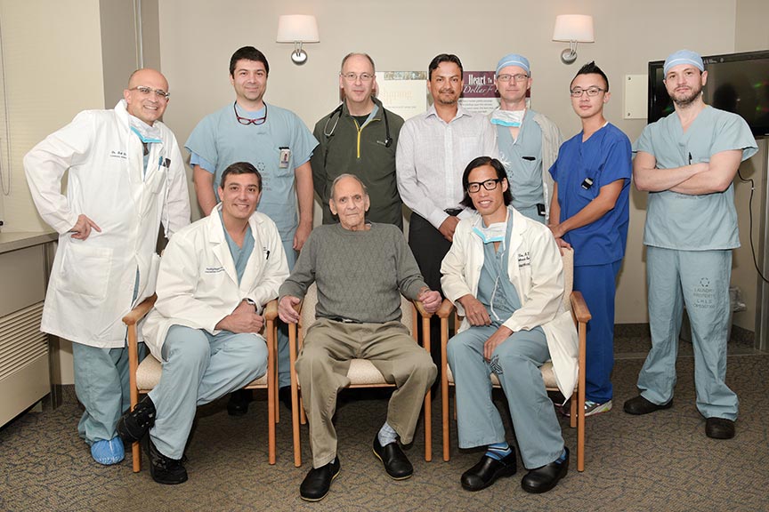 Group of male physicians and nurses gathered around a male patient.