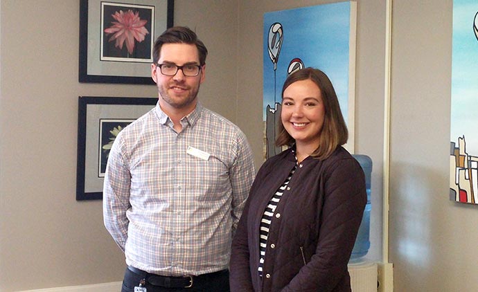 Male and female in front of three framed paintings.