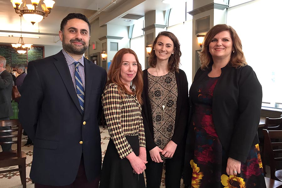 Three females and one male dressed in business attire.