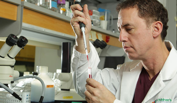 Dr. Douglas Fraser using a dropper to put fluid into a test tube in a hospital laboratory.