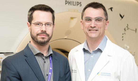 Dr. Aaron Ward and Dr. Glenn Bauman standing in front of an MRI machine. 