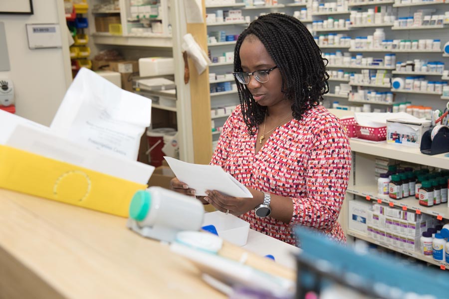 Female nurse standing behind desk reading document.