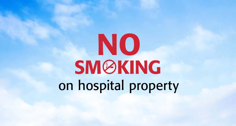 “No smoking on hospital property” in red and black text on top of a blue sky with clouds background.