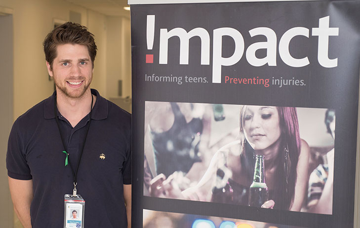 Man pictured with Impact program poster.