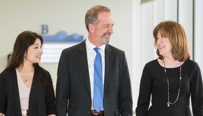 Three executive team members pictured walking beside one another.