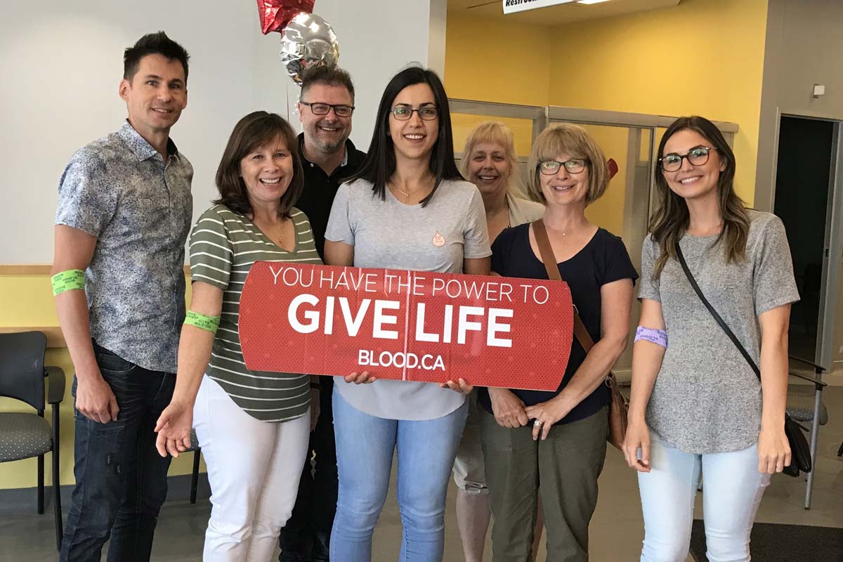 Blood donors holding a sign that says “you have the power to give life.”