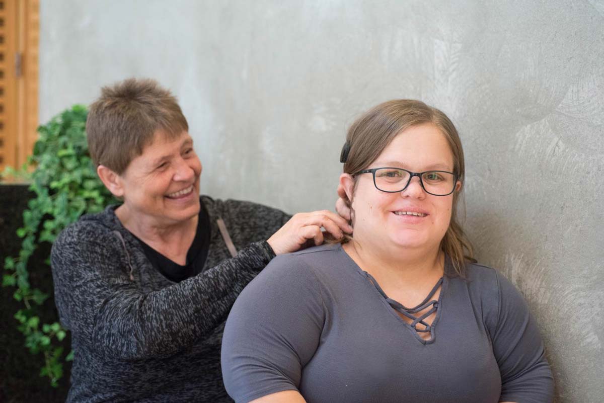 Laura Sitlington looking at the camera while a woman holds her hair back.