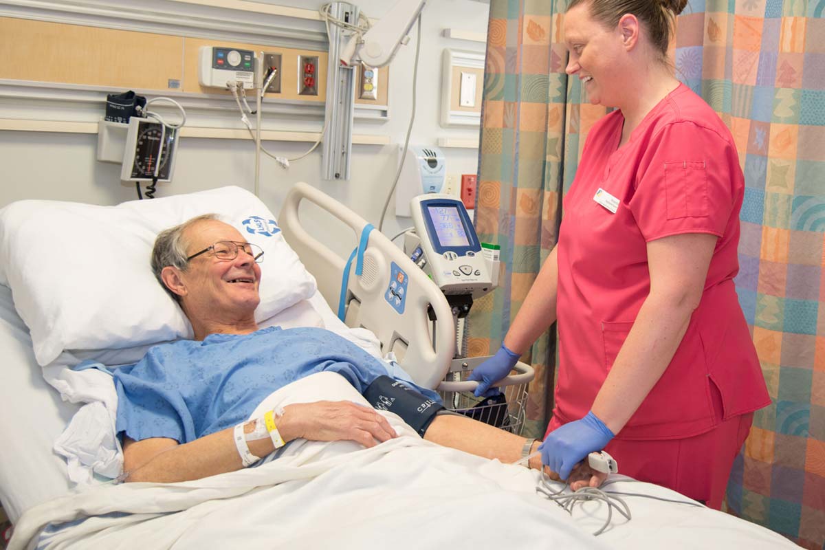 A man in a hospital bed and a nurse taking his blood pressure.