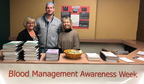 Three Medical Professionals stand above a banner reading Blood Management Awareness Week