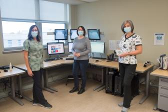 Three Sleep Medicine staff standing in front of computers wearing masks.