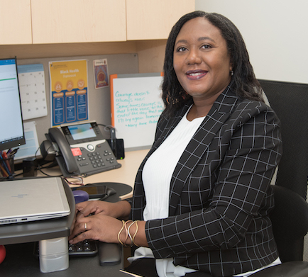 A photo of Cathy Wood, Senior Director of Black Health, sitting at a desk with a computer