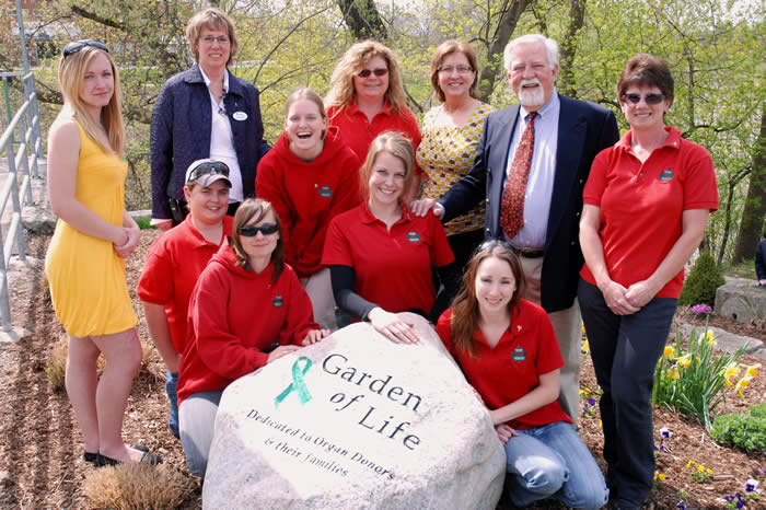 Patients, staff and volunteers gathered around a stone commemorating the Garden of Life. 