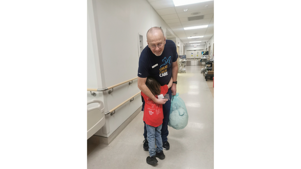 A healthcare professional hugs a child who is a former patient.