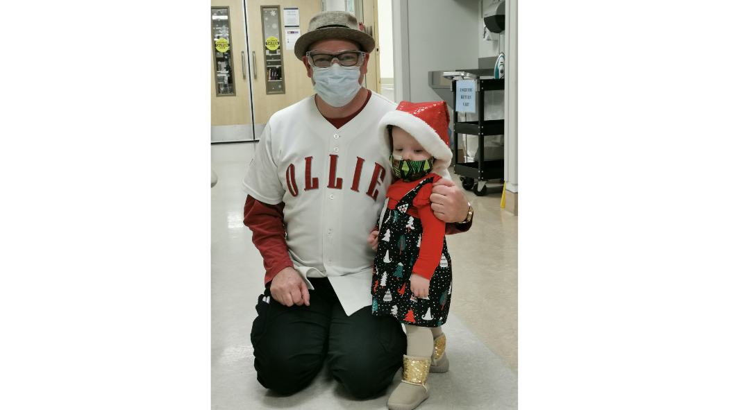 A therapeutic clown and a small child pose together for a photo.
