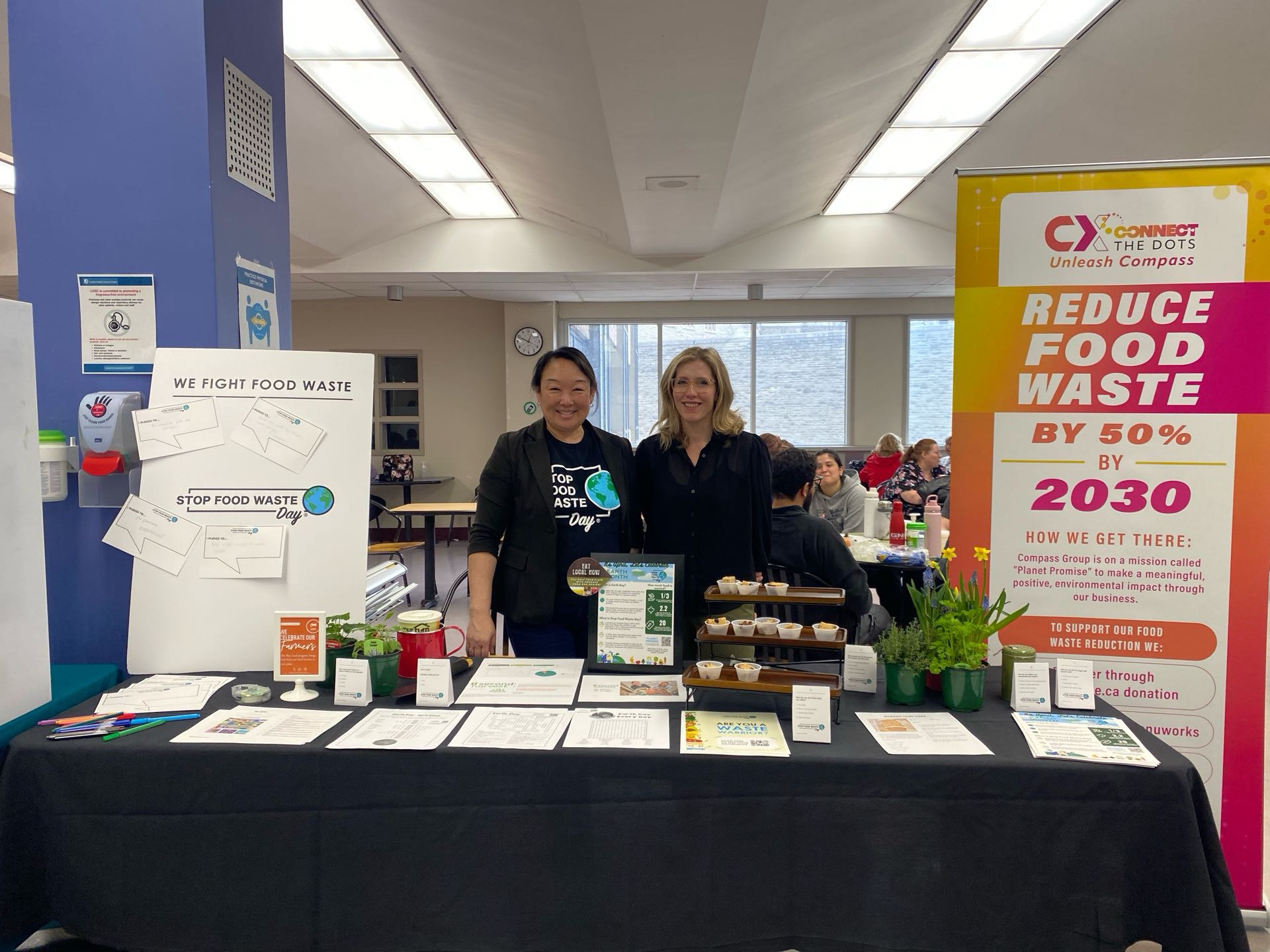 Compass Group team members Jennifer Lambert, Sustainability Director (left) and Sarah Magowan, General Manager - University Hospital (right) showcasing their "Stop Food Waste Day" target at the 2024 LHSC Earth Day Fair.