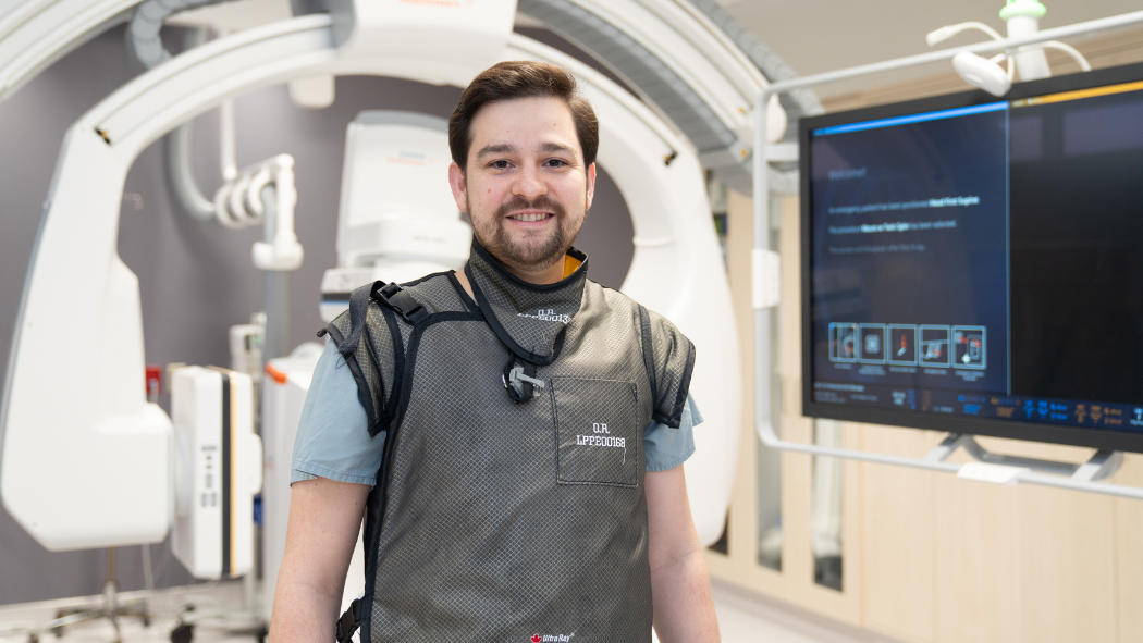 a physician stands in a clinical space wearing protective clothing