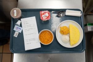 A diabetic meal is served on real dishware with a printed ticket noting carbohydrates and fibre to help a patient with diabetes determine their insulin dosage