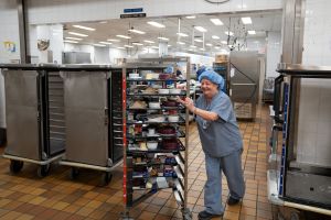 A dietary worker heads out for tray delivery