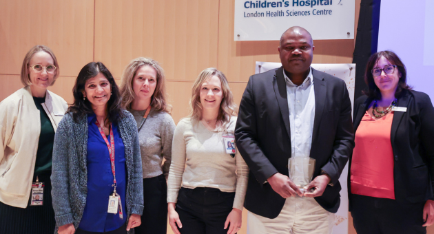 People stand smiling at camera while one holds an award