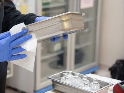 hands using a disinfection wipe to clean metal tray