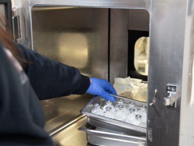 person placing a tray of vials into a metal box