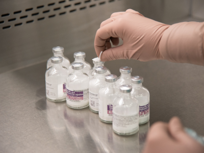 technician taking seals off medication vials