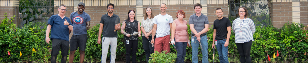 LHSC Green Team members and hospital staff posing for a photograph in front of the newly planted pollinator garden.