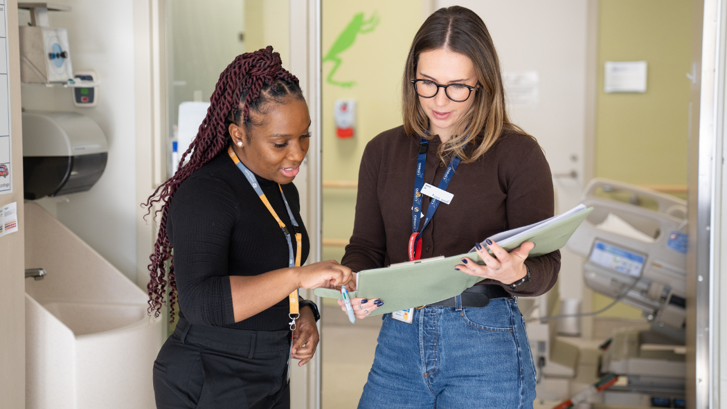 Two women discussing a document in a clinical setting.