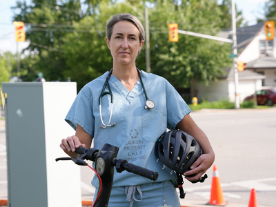 Dr. Belisle in scrubs with escooter and helmet