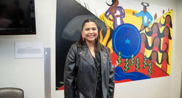 Destiny Elijah stands in front of her mural in the Mental Health Indigenous Healing Space.