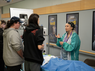 LHSC Operating Room staff member talks with two students at the Youth Indigenous Career Fair. 