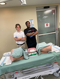 Two BETTY team members stand with Urinary Catheterization dummies