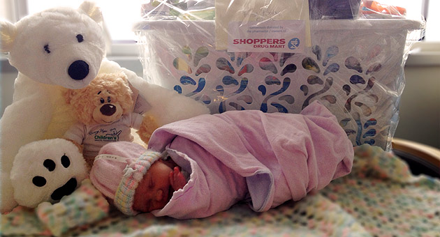 Baby Serena, first baby born at LHSC in 2014, with gift basket and bears