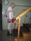 Image of a man demonstrating how to go up the stairs with two crutches