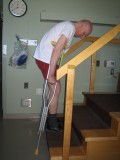 Image of a man demonstrating how to go up the stairs with two crutches