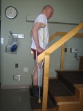 Image of a man demonstrating how to go up the stairs with two crutches