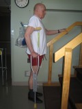 Image of a man demonstrating how to go up the stairs with one crutch and using a railing